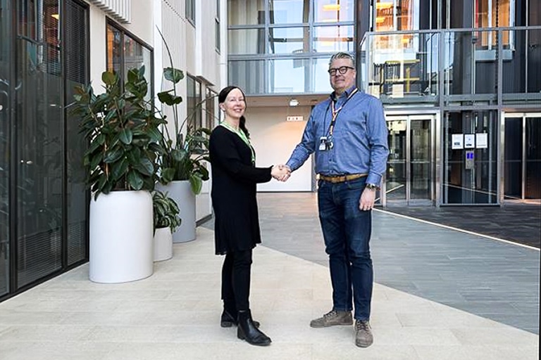 Nainen ja mies kättelevät toimistotalon aulassa iloisin mielin.